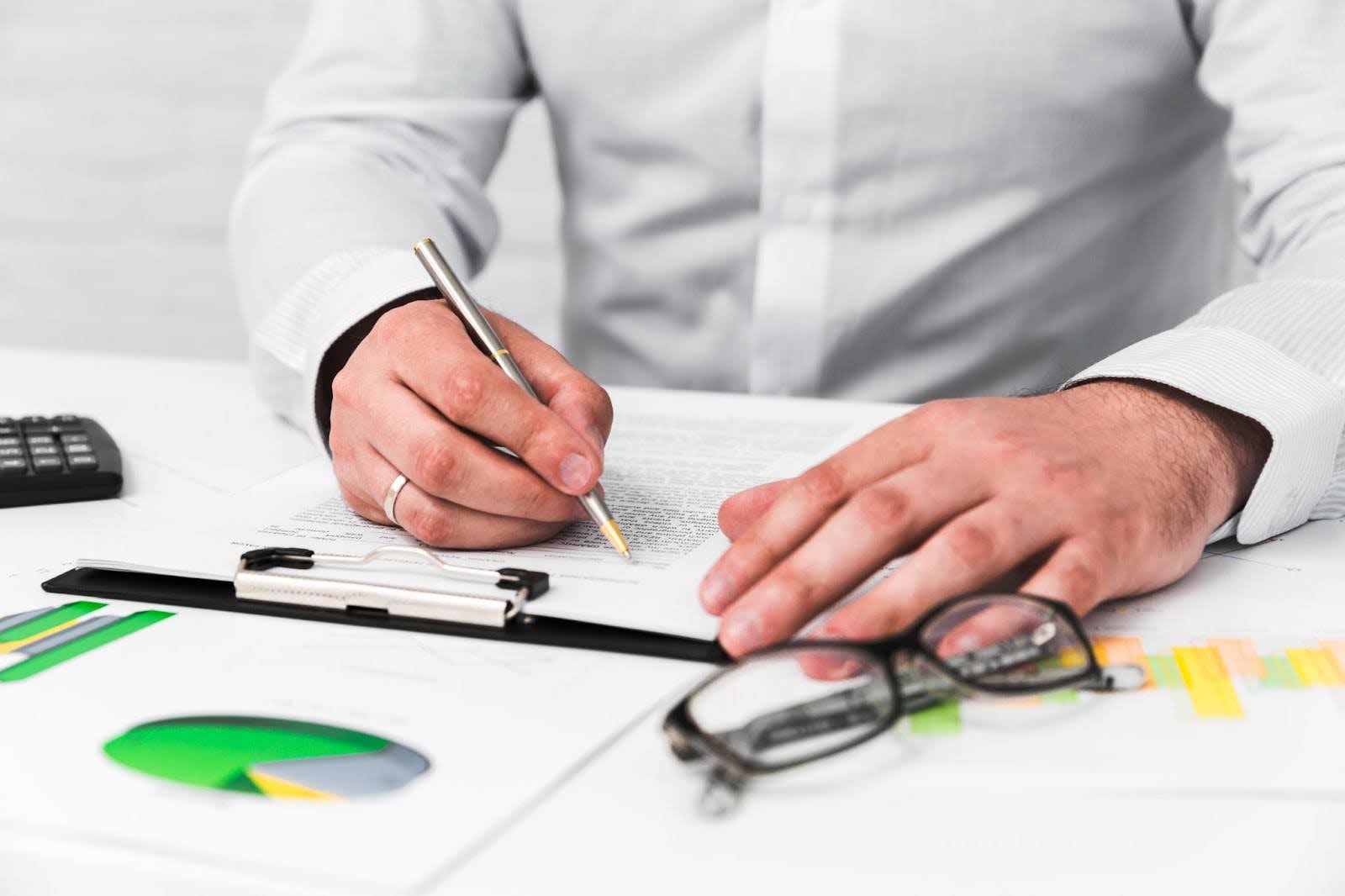 Business professional reviewing and signing compliance documents in fintech office environment